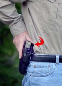 The author demonstrates drawing the CP99 Compact from the Safariland ALS holster. Note the thumb depresses the locking release (arrow) as the pistol is drawn. Also note the position of the trigger finger on the outside of the holster.