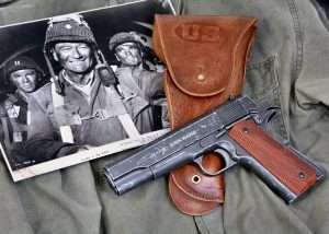 The new John Wayne Model 1911A1 is the first John Wayne semi-auto in the series of John Wayne commemorative airguns. (Shown with a publicity photo of Wayne in The Longest Day, and a copy of a WWII era JT&L Model 1942 holster from World War Supply). 