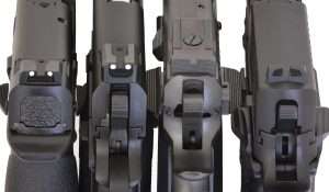 Four different rear sight designs are compared in this final evaluation. From left to right, the Umarex S&W M&P40 uses a shallow, wide recessed U notch bordered with deeply inset white dots. The Umarex Colt Commander uses a dovetailed combat (Novak) style rear sight with a recessed U channel and deeply inset bright white dots on either side. The Tanfoglio Limited Custom is equipped with a windage and elevation adjustable dovetailed rear sight similar to a Dawson Precision Bomar-style using a black horizontally serrated wide U notch. The Sig Sauer P226 X-Five has a tall black rear sight that has an inward V-angled notch. The sides reflect light to slightly illuminate the rear notch and quickly frame the white dot front sight.
