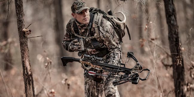 hunter with crossbow stalking prey in the woods