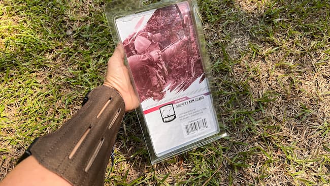Bear Archery Cordura Arm Guard shown on archer's arm with packaging.