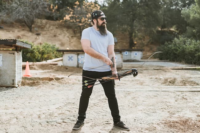 archer holding a recurve bow with attached quiver getting ready to draw.