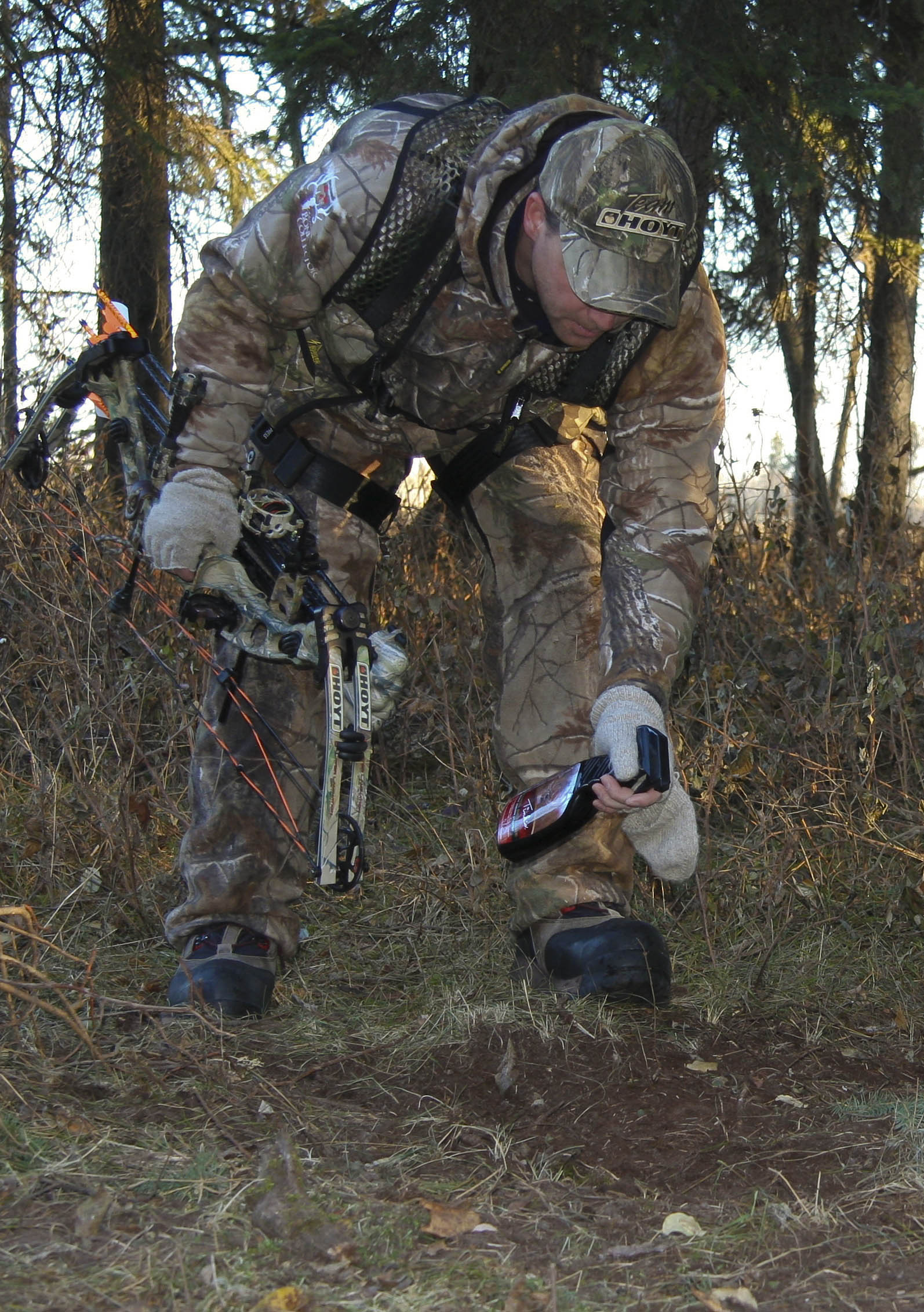 bowhunter spraying ground scrapes with scent bait