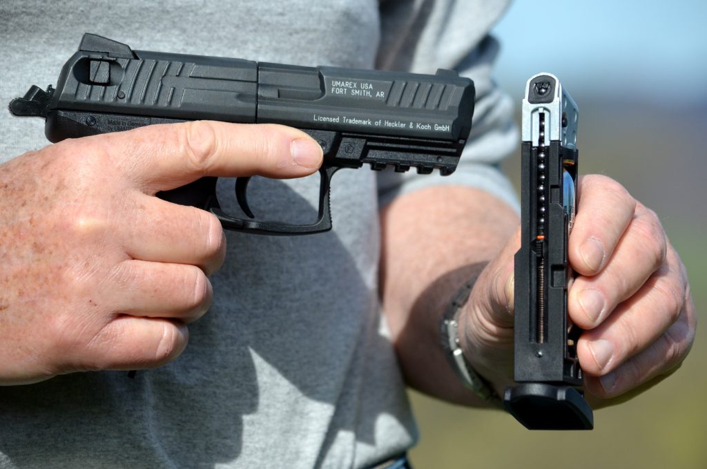 Denis Adler holding the pistol in his right hand and the magazine showing the BBs in his left hand.