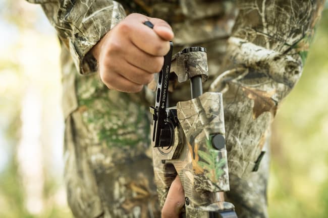 Hunter using crank to cock the crossbow.