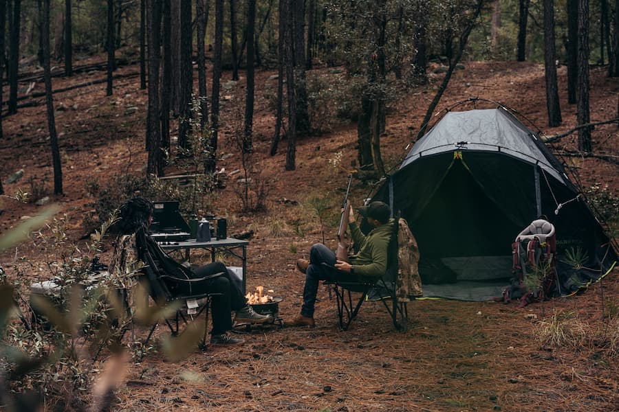campsite with a tent, bags, camp stove, and other gear that facilitates a good hunting and camping adventure.