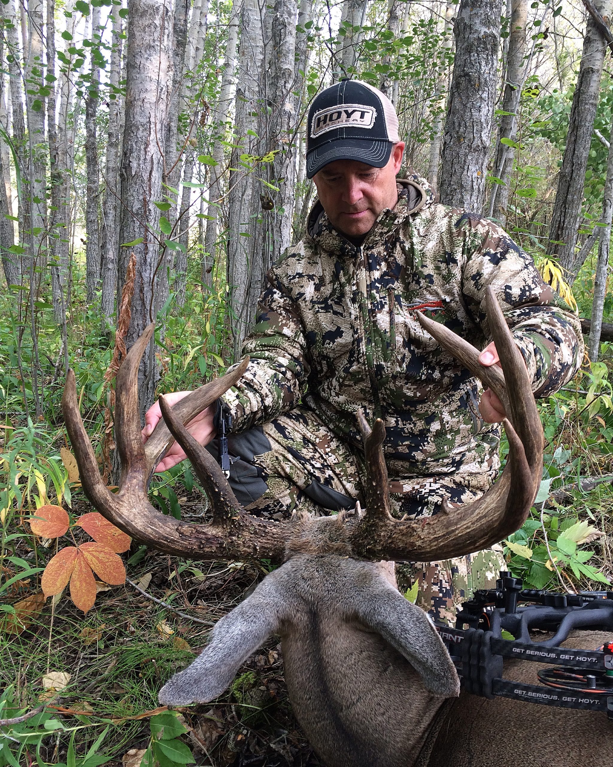 Kevin Wilson examining the buck he arrowed near a corn field in low light.