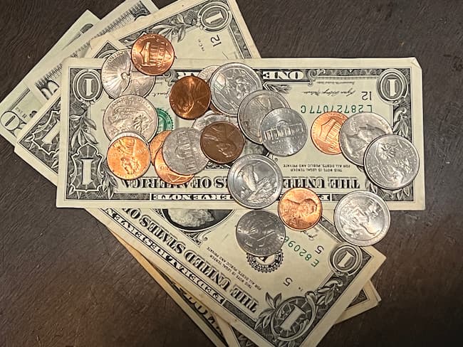 Pile of money, smaller bills on top of larger bills topped with coins