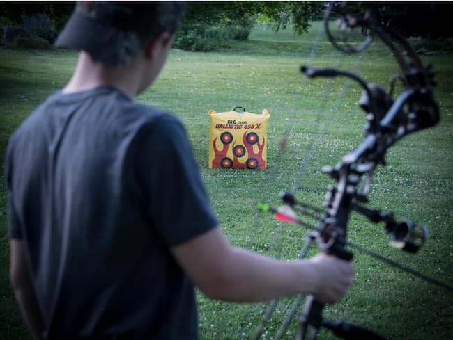 big shot target in background, archer preparing to shot in foreground