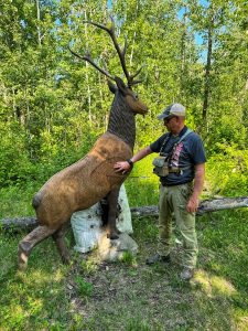 kevin wilson standing beside a buck 3d target showing arrow penetration.