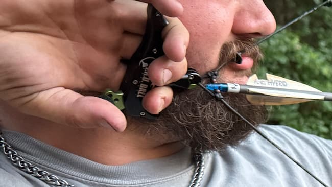 closeup of archer in full draw with release next to his face